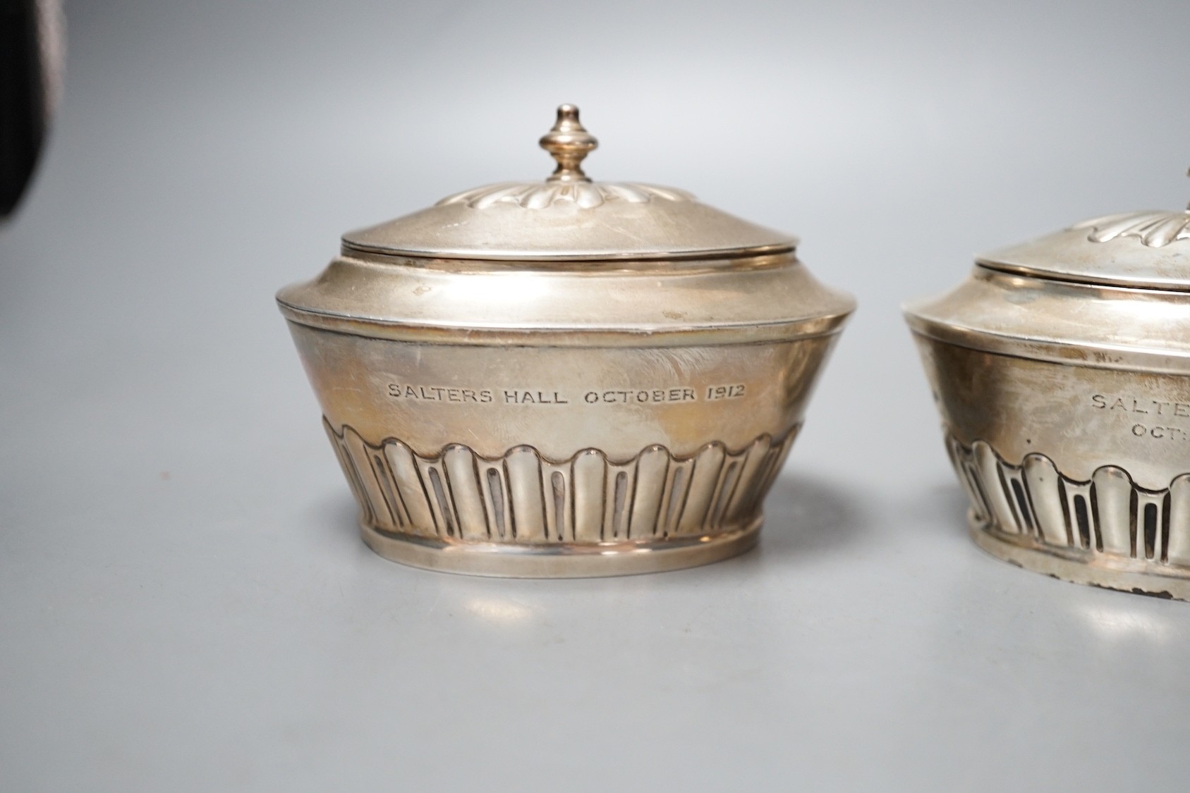 A matched pair of early 20th century silver oval tea caddies, London, 1908 & 191, width 10.5cm and two early 20th century silver leaf caddy spoons, one Britannia standard.